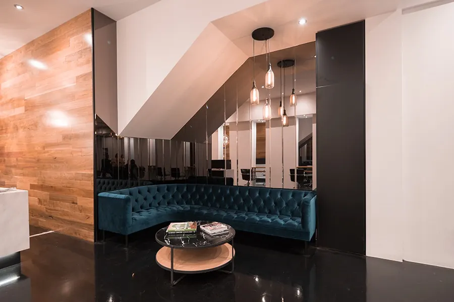 The teal velvet lounge and timber walls in Room 53's waiting area